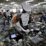 Humanoid robots work side by side with employees in the assembly line at a factory in Japan. Photo credit: Reuters/Issei Kato